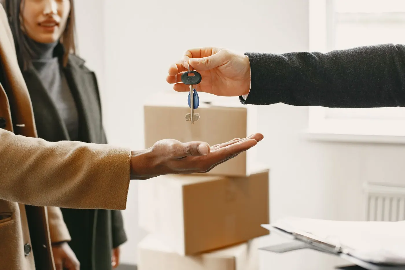 House keys being handed over beside moving boxes